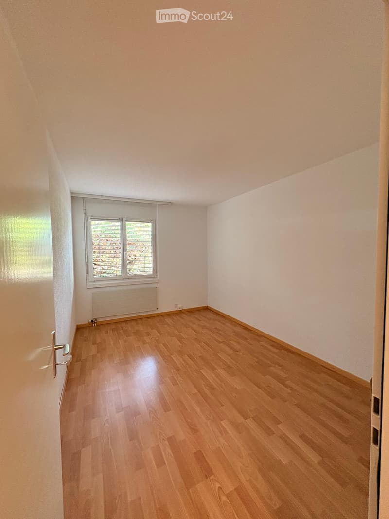 Empty room with light wooden flooring, white walls, and a window with blinds. No furniture or equipment is present.