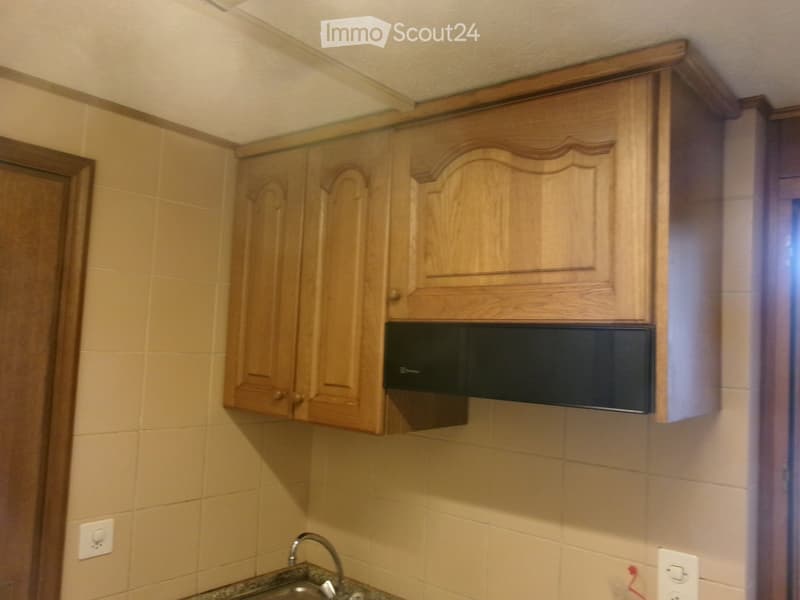 A small kitchen with light wooden cabinets, a microwave, and a sink with a faucet.