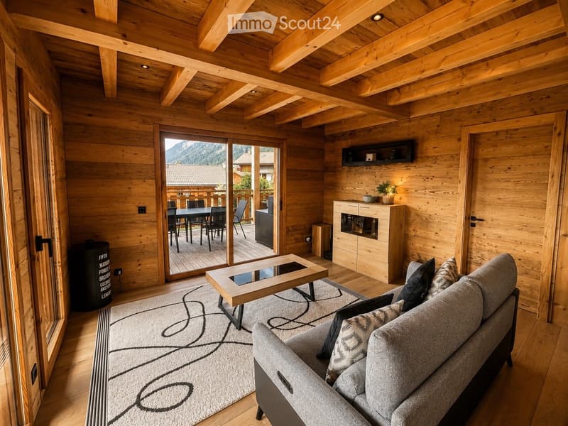 Cozy living room with exposed wooden beams, a grey sofa, coffee table, dining area with table and chairs, and a view of the mountains through large glass doors.