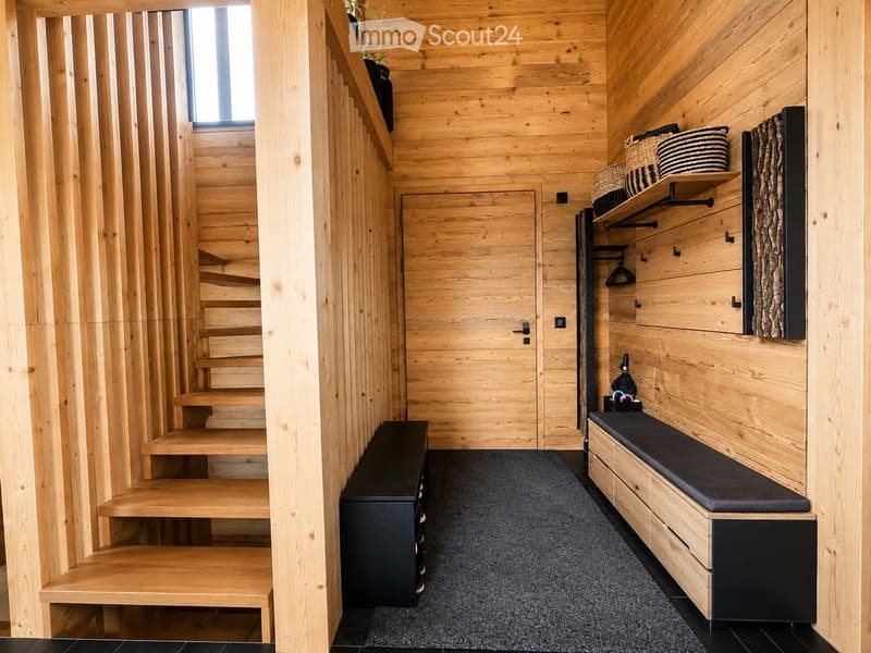 Wooden hallway with built-in bench, shelves, and staircase leading upwards.