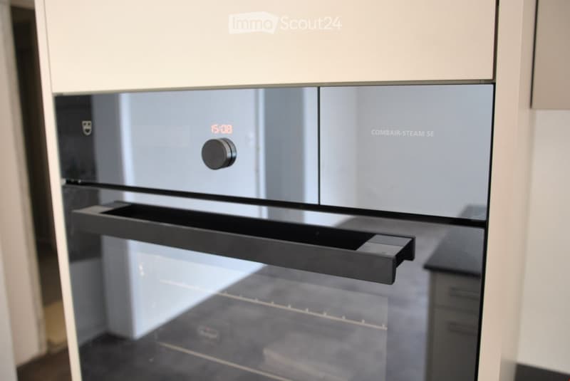 Modern kitchen with a sleek, stainless steel oven featuring a digital display showing the time and a control knob.