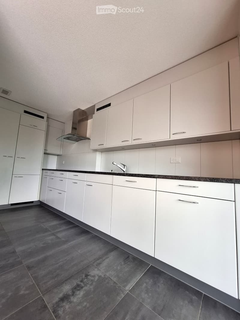 Modern kitchen with white cabinets, dark countertops, and a stainless steel faucet.