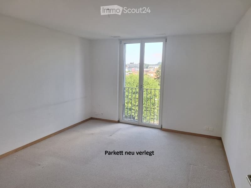 Empty room with white walls, carpeted floor, and large sliding glass door leading to a balcony.
