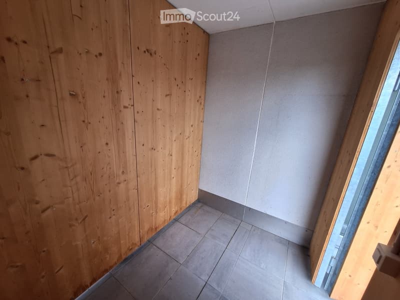 Empty room with wooden walls, tiled floor, and a window allowing natural light to enter.