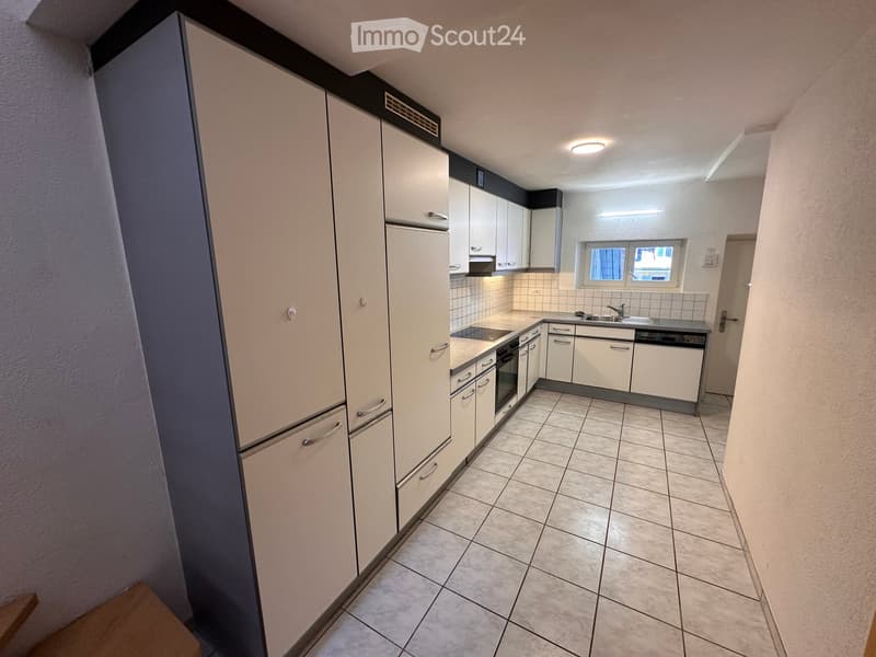 Modern kitchen with white cabinets, stainless steel appliances, tiled floor, and a window above the sink.