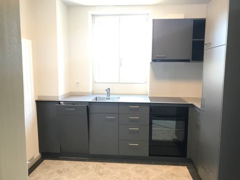 Modern kitchen with dark grey cabinets, a sink, and an oven. The space is clean and well-lit with a tiled floor.