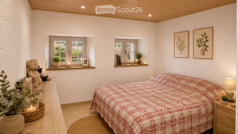 Cozy bedroom with a wooden ceiling, white walls, and large windows. Features a bed with a red and white checkered blanket, a nightstand with a lamp, and decorative items including plants, books, and picture frames.