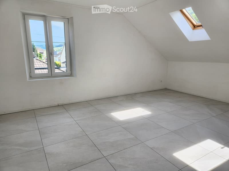 Empty room with tiled floor and white walls, featuring a large window and a skylight.