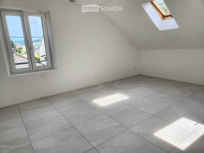 Empty room with tiled floor and white walls, featuring a large window with a view and a skylight.