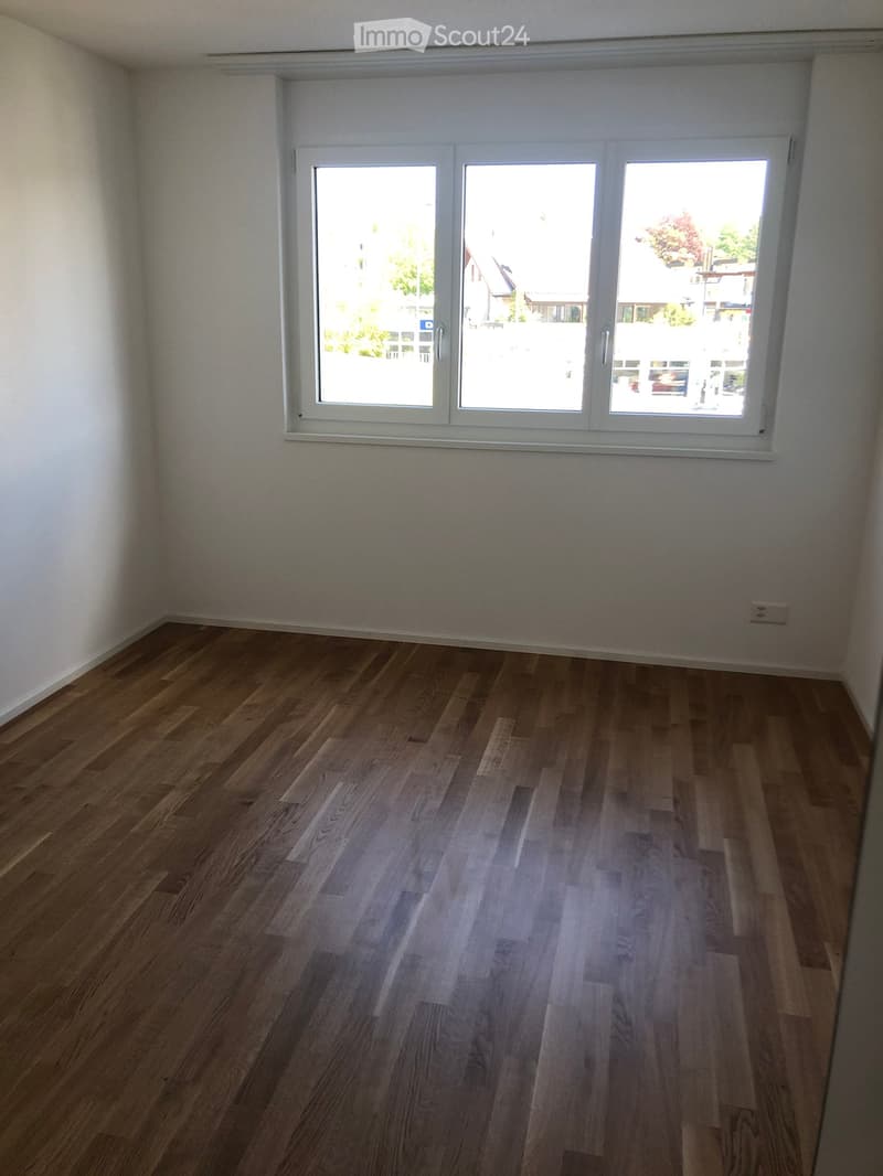 Empty room with wooden flooring and large windows, no furniture or equipment present.