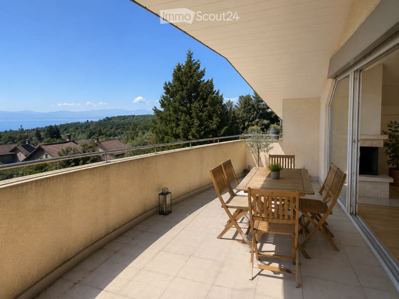 Balcony with wooden table and chairs, overlooking a scenic view of a lake and mountains.