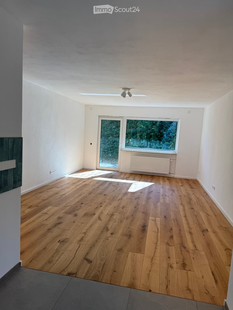 Empty room with wooden flooring, white walls, large windows, and a radiator. No furniture or equipment present.