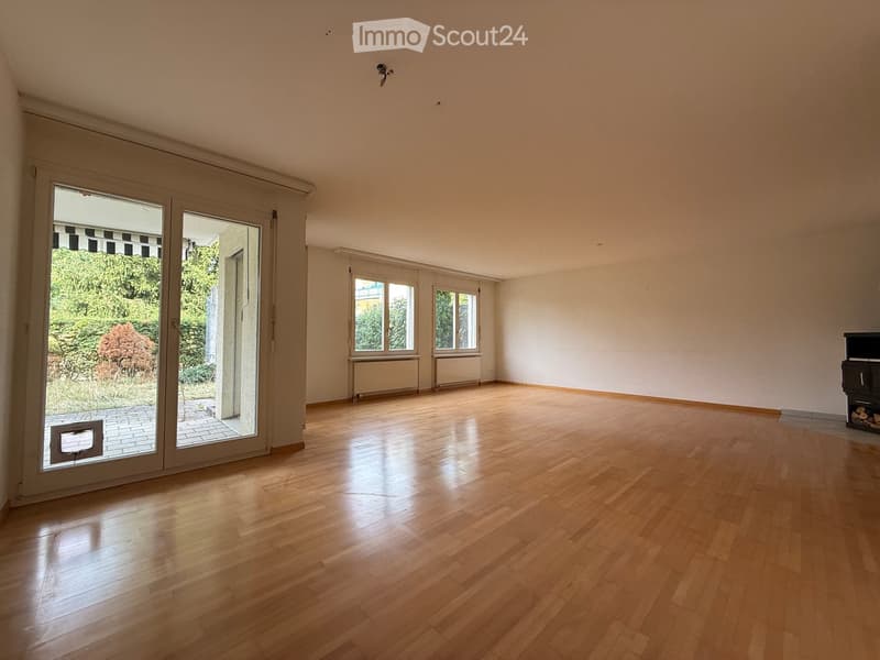 Empty room with wooden flooring, large sliding glass doors leading to a patio, and white walls.