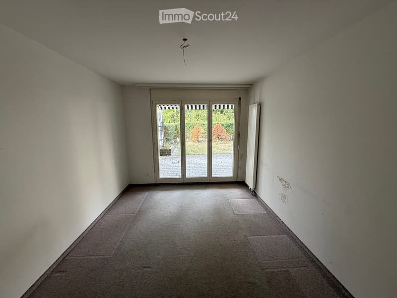 Empty room with white walls, carpeted floor, and large sliding glass doors leading to an outdoor area.