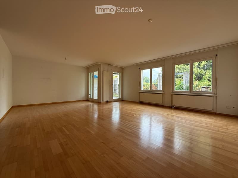 Empty room with wooden flooring, large windows, and radiators along the walls. No furniture or equipment present.