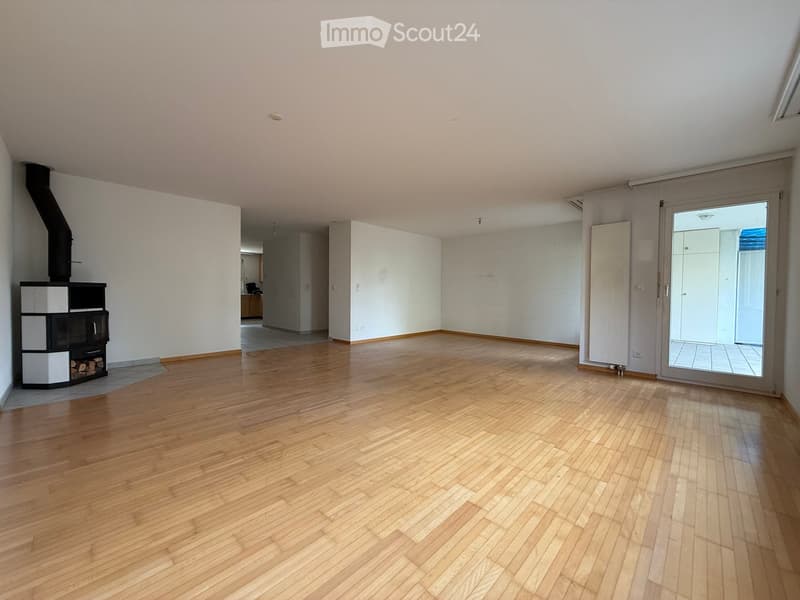 Empty room with wooden flooring, white walls, and a fireplace with a chimney. A sliding glass door leads to an outdoor area.
