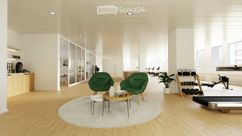 Modern, well-lit room with wooden flooring, white walls, and recessed lighting. Features a green sofa, coffee table, small stool, round rug, potted plant, kitchen area with counter and cups, and exercise equipment including a treadmill and weight rack.