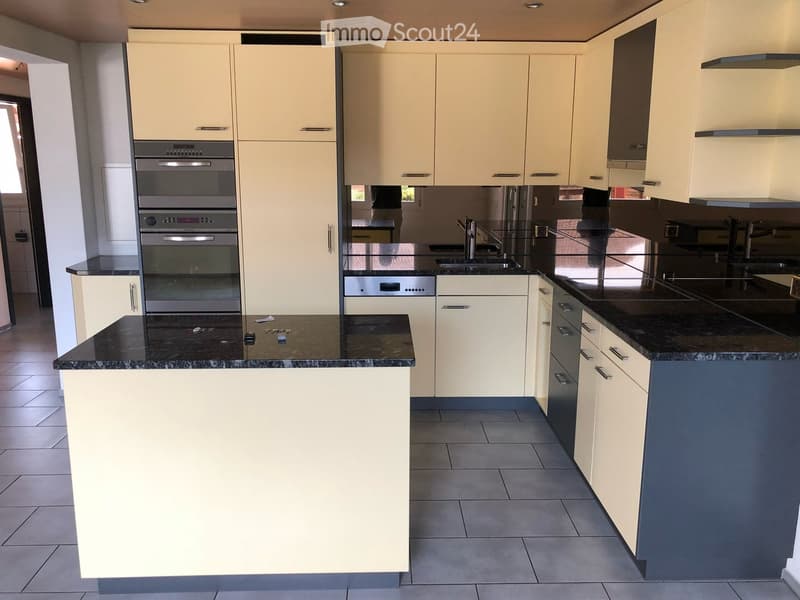 Modern kitchen with light-colored cabinets, stainless steel appliances, and a black granite countertop.