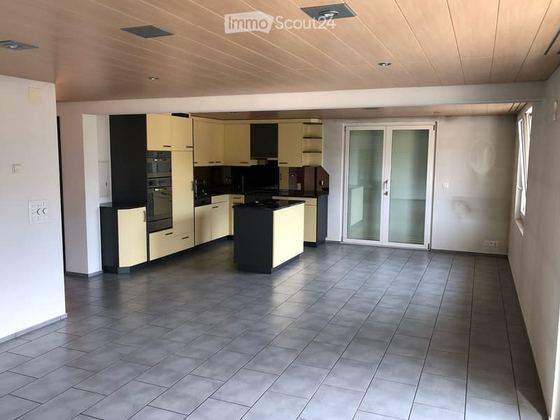 Modern kitchen with light-colored cabinets, stainless steel appliances, and a black countertop. Features a large sliding glass door leading to an outdoor area.