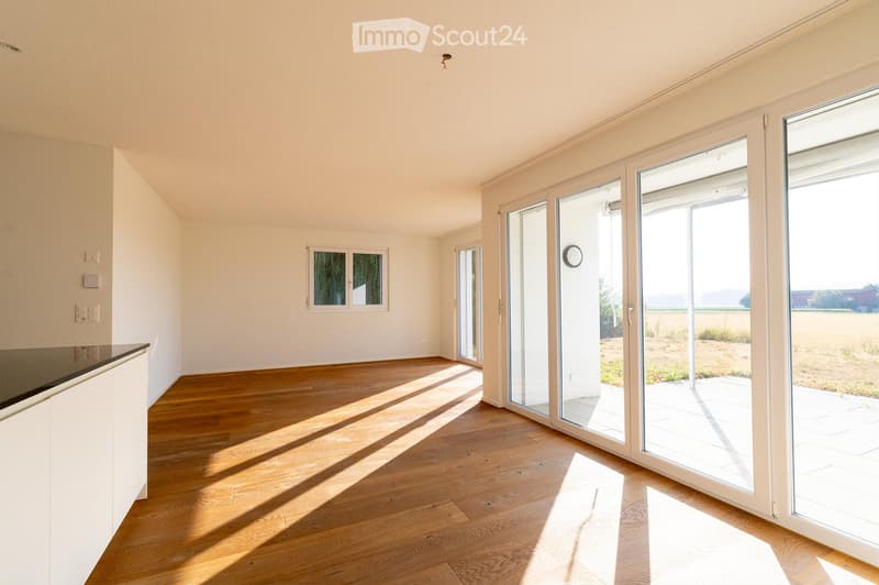 Empty room with wooden flooring, white walls, large sliding glass doors, and a small window. No furniture or equipment present.