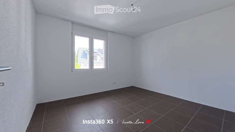 Empty room with white walls, dark tiled floor, and a window with white frame. No furniture or equipment present.