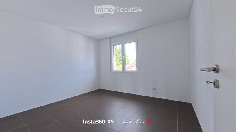 Empty room with white walls, dark tiled floor, and a window with blinds. No furniture or equipment present.