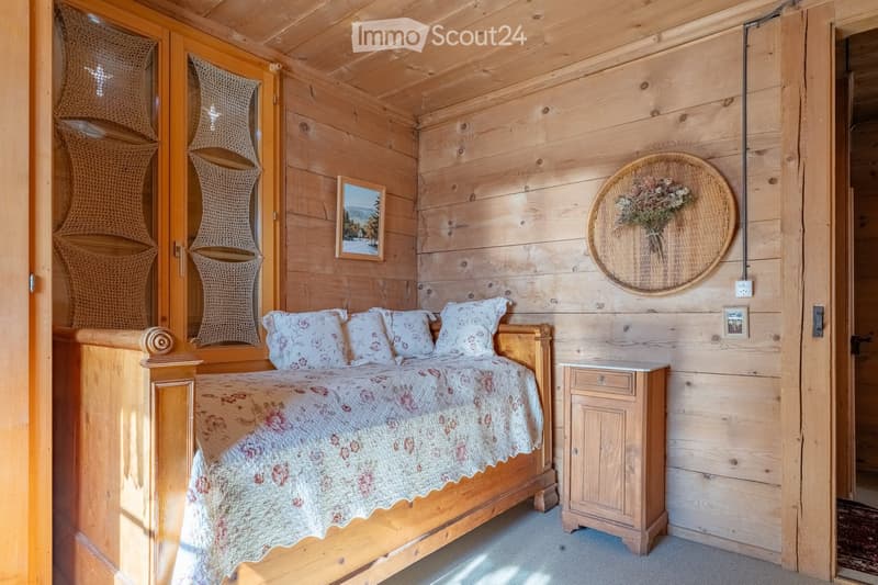 Cozy wooden bedroom with a large bed, nightstand, picture frame, and wicker basket on the wall.