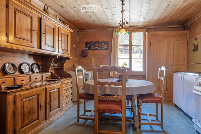 Cozy wooden dining room with a round dining table, chairs, wooden cabinets, and a chandelier.
