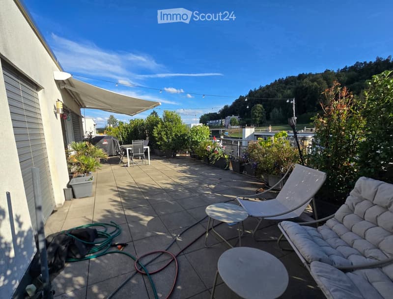 Balcony with tiled floor, covered area, outdoor furniture including a sofa, chairs, tables, and potted plants.