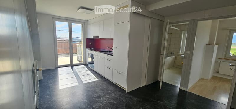 Kitchen. Modern kitchen with white cabinets, black countertops, and a red accent wall. Equipped with a sink, faucet, and a large window.