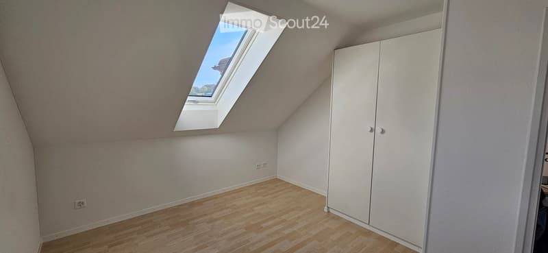 Unfurnished Room. Empty room with wooden floor, white walls, and a skylight window. A wardrobe is present but empty.