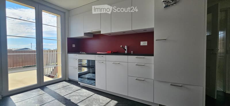 Kitchen. Modern kitchen with white cabinets, red backsplash, and a glass door leading to a balcony.