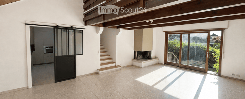 Bright hallway with wooden ceiling beams, tiled floor, sliding glass door leading to outdoor area, staircase, and fireplace.