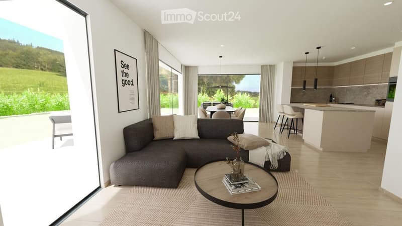 Modern living room with large windows offering a scenic view, featuring a dark gray sectional sofa, a round coffee table, a kitchen area with a white island, and a dining area with a table and chairs.