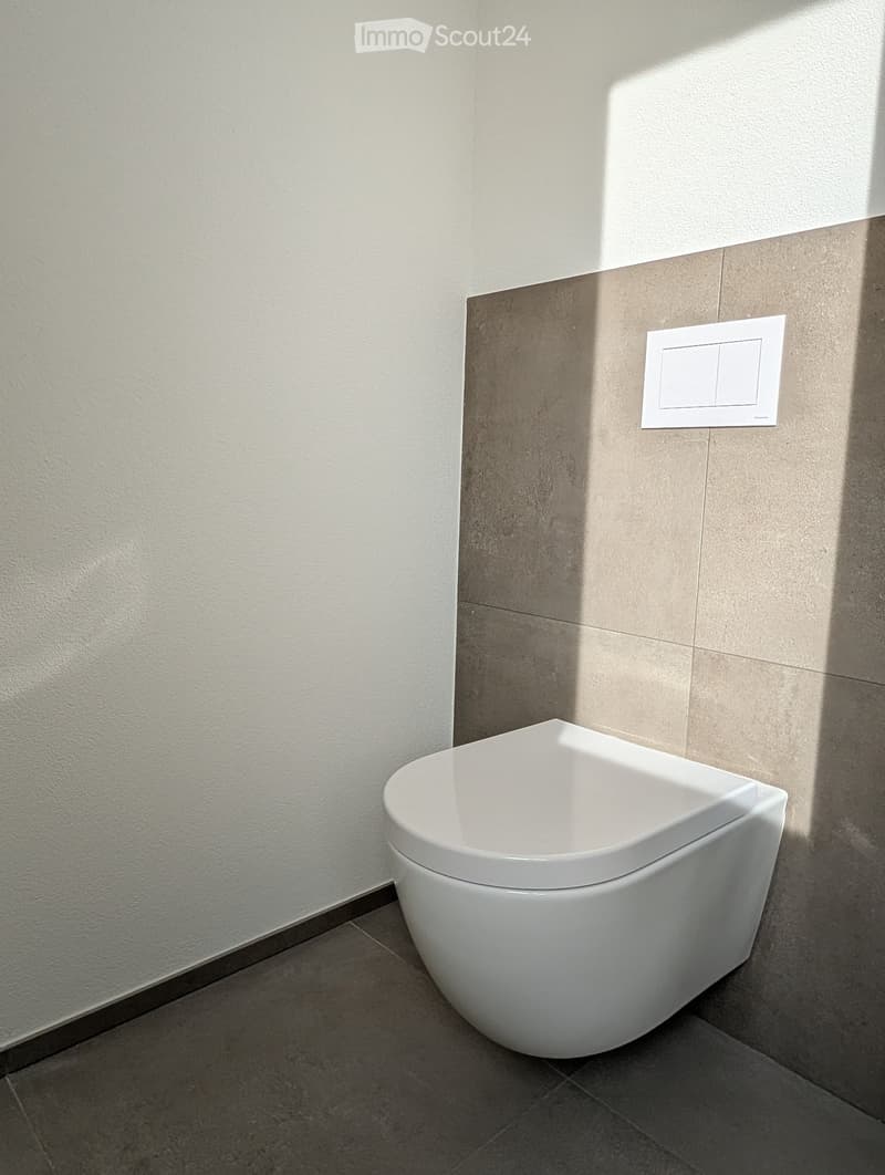 Modern bathroom with a white toilet, beige tiled walls, and a control panel above the toilet.