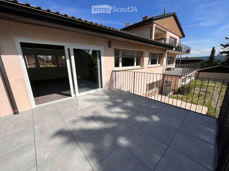 Balcony with tiled floor, metal railing, and sliding glass doors leading to the interior.