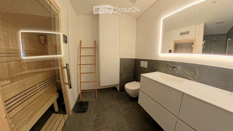 Modern bathroom with a sauna, sink, toilet, and mirrored cabinets with LED lighting.