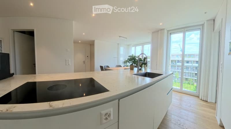 Modern kitchen with white cabinets, marble countertop, induction cooktop, sink, and large windows with a view of the city.