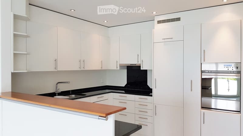 Modern kitchen with white cabinets, stainless steel appliances, and a wooden countertop.