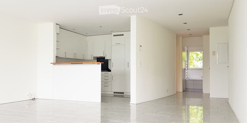 Modern, minimalist kitchen with white cabinets, a wooden countertop, and a tiled floor. The space is clean and uncluttered, with no visible furniture or appliances.
