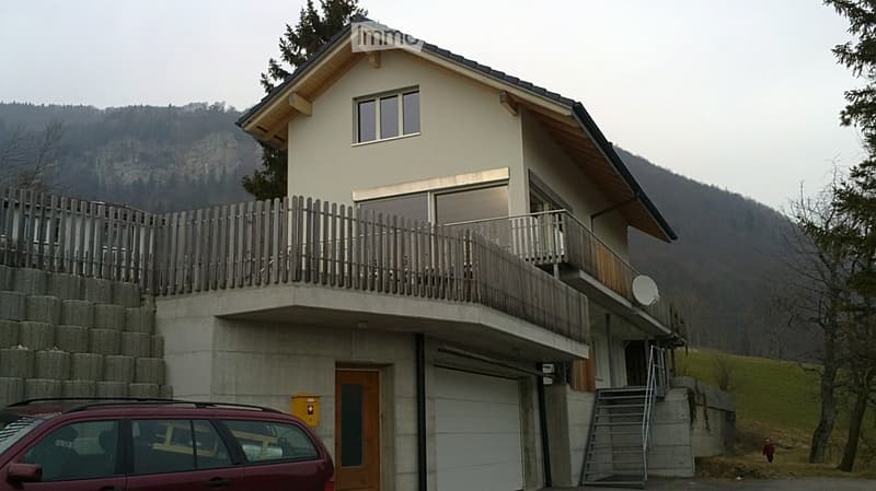 Two-story house with a balcony, garage, and scenic mountain view in the background.