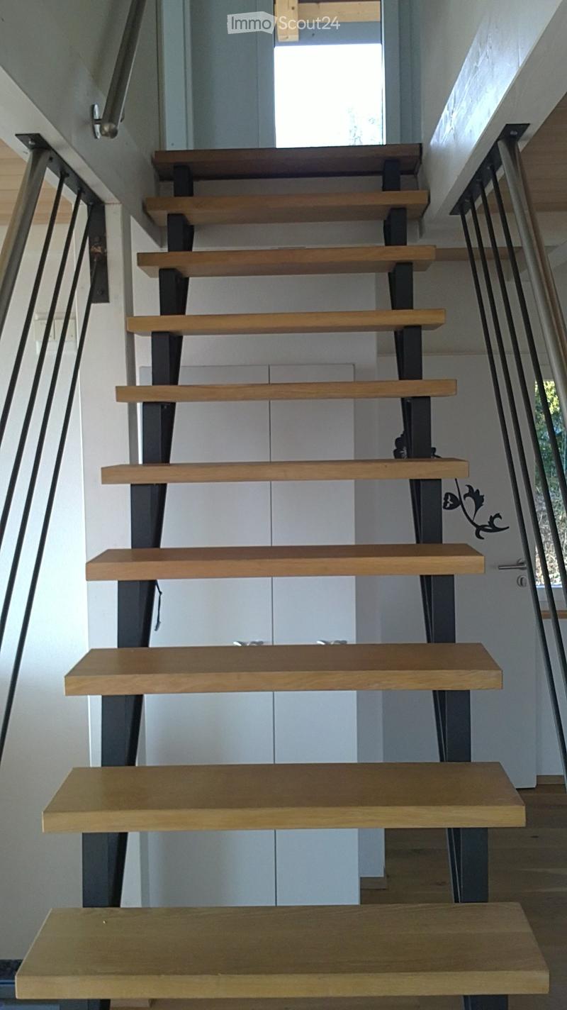 Modern staircase with wooden steps and metal railings, leading upwards with natural light from the side windows.