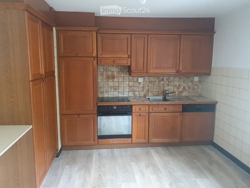 Modern kitchen with wooden cabinets, a stainless steel oven, a sink with a faucet, and a tiled backsplash.