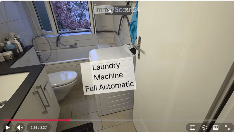 Compact bathroom with a toilet, sink, and a full-automatic washing machine. The space includes a countertop with various toiletries and a window providing natural light.
