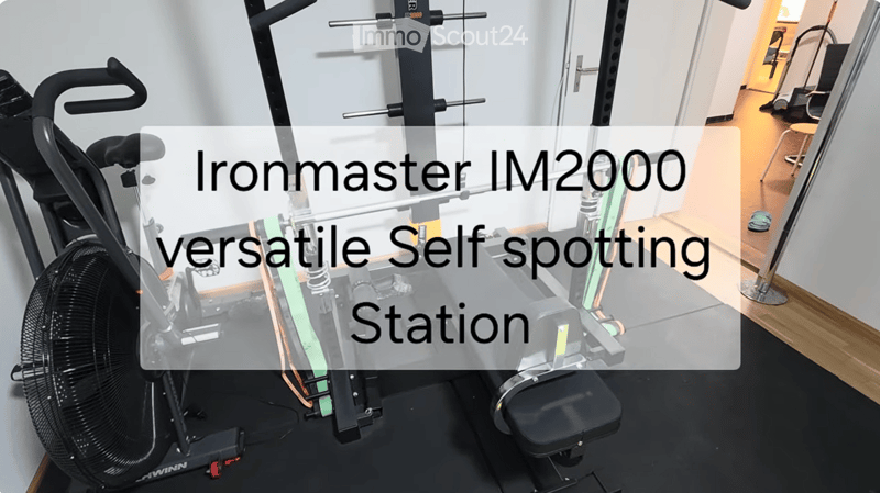 A modern gym room with an Ironmaster IM2000 versatile self-spotting station, a weight rack, and a stool.