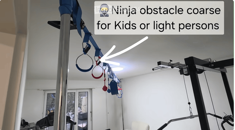 A room with a gymnastics obstacle course, including rings, parallel bars, and a pull-up bar, with a large window and a weight rack in the background.