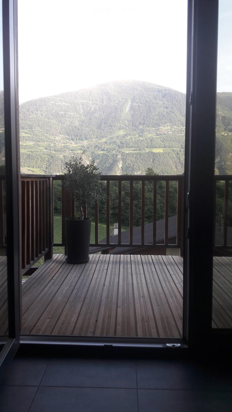 Wooden balcony with a railing, a potted plant, and a scenic mountain view.