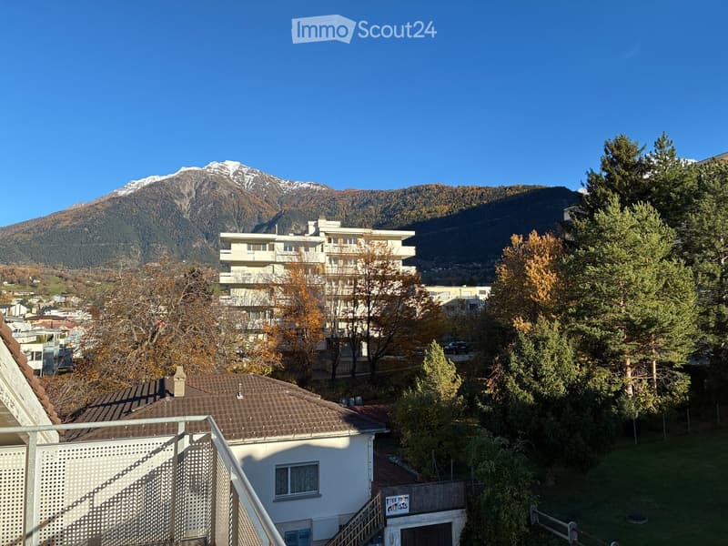 Balcony with view on houses, mountains, and trees.
