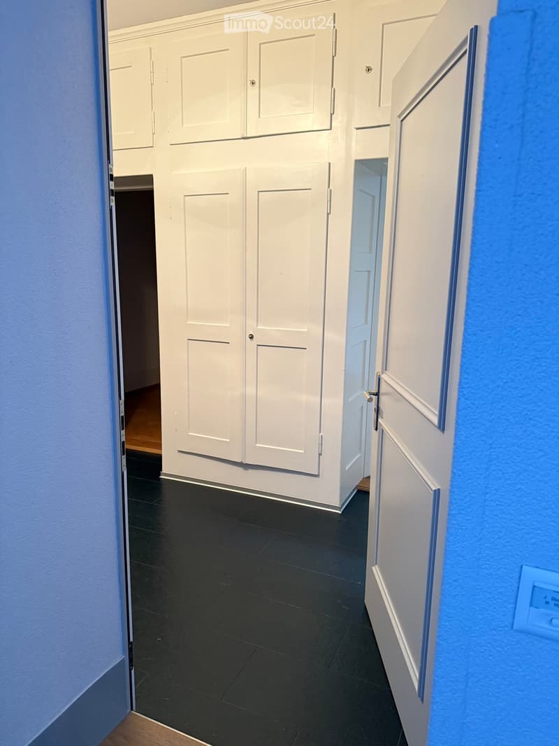 open door with hallway leading to large closets and a passageway with an open door leading to another room