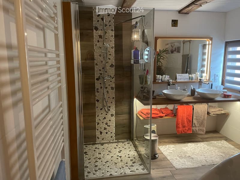 Modern bathroom with a glass-enclosed shower, mosaic tile accents, double sink vanity, and neatly arranged towels.